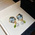 Vista macro de pendientes de flores de esmalte azul con perlas y detalle de hoja - Poste de plata - Dorado - Azul