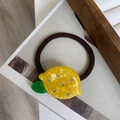 Détail de l'élastique cheveux citron jaune avec strass et feuille verte sur lien marron - Citron