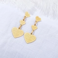 Orecchini pendenti a tre cuori dorati con texture opaca su sfondo bianco morbido - Oro
