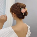 Detailed view of elegant gold metal hair claw with pink fabric flowers on a low bun - Pink Rose Flower Claw Clip
