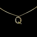 Macro shot of 18k gold letter Q pendant featuring colorful inlaid zircon stones - Letter Q / Gold