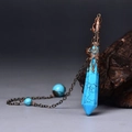 Macro shot of turquoise hexagonal point pendant with antique bronze filigree cap on wood - Antique Bronze Blue Turquoise