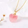Gros plan d'un collier avec pendentif coeur en cristal rose et chaîne dorée texturée - Rose