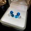 Detailed view of blue faceted crystal and white pearl stud earrings in a beige jewelry box - Blue Gem Pearl Geometric Triangle Studs (29#)