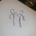 Macro shot of silver bow earrings with sparkling cubic zirconia on a gray leather texture - Ear Hook Style / Silver
