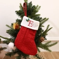 Red knit Christmas stocking with white cuff featuring embroidered letter E and holly leaf - Letter E