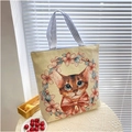 Detailed view of beige canvas tote bag featuring floral cat embroidery and striped handles - Wreath Bow Cat