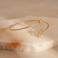 Dettaglio macro del bracciale rigido dorato aperto con ciondoli a forma di sole e luna - Stile Sole Dorato (HB100)