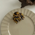 Close-up of tortoise shell pattern claw clip on a ceramic plate with wooden background - Ghost Hand Claw