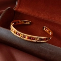 Detailed macro view of gold plated open bangle with colorful stone beads in a velvet box - Gold