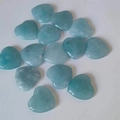 Polished heart-shaped aquamarine crystals scattered on a clean white background - Synthetic Aquamarine