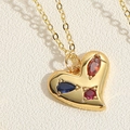 Macro shot of gold heart pendant with colorful zircon gemstones on a white textured background - Three Colorful Zirconia (XL2638-4)