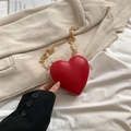 Red heart-shaped mini crossbody bag with gold chain strap on beige blazer background - Red