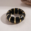 Detailopname van een grove acryl stretch armband in contrasterend zwart en goud ontwerp - Zwart
