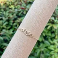 Close-up of interlocking gold heart charms with pavé cubic zirconia on a link bracelet - Interlocked Hearts