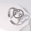 Detailed view of silver abstract face hollow ring on a white textured rock background - Adjustable / Steel