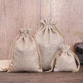 Three natural linen drawstring gift pouches in various sizes on a wood background - Beige Grey