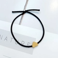 Detalle de un coletero elástico negro con un colgante minimalista en forma de corazón amarillo - Corazón Amarillo Brillante