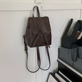 Détail d'un sac à dos vintage en similicuir marron avec rabat et cordon sur un crochet - Brun Vintage