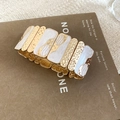 Dettaglio del bracciale elastico largo con finitura dorata martellata e smalto marmo bianco - Oro-Bianco