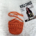 Close-up of orange handmade woven cotton rope bag with textured knit and silver metal buckle - Orange