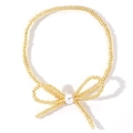 Dettaglio del bracciale a fiocco con perline dorate e una perla bianca centrale lucida - Grani Dorati + Fiocco con Centro in Perla