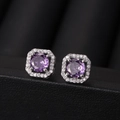 Macro shot of silver stud earrings with purple gemstone and cubic zirconia halo setting - Purple