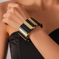 Nahaufnahme eines breiten geometrischen Stretch-Armbands mit schwarzen und goldenen Acrylteilen - Schwarz und Gold gespleißter Stil