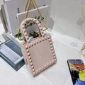 Detailed shot of pink PVC mini crossbody bag with studs on a stylish bookshelf - Apricot
