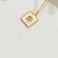 Detail of a gold necklace with a white enamel square pendant featuring a 3D floral motif - White Flower