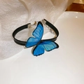 Dettaglio della collana girocollo con farfalla blu su un vassoio di ceramica bianca - Bracciale Farfalla Blu