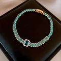 Detail of gold tennis bracelet with sky blue zircons and deep blue emerald-cut stone - Blue