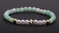 Détail du bracelet en perles avec cristaux verts, perles et pendentif croix dorée - Croix Verte