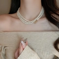 Detail of multi-layered pearl necklace featuring a classic gold OT toggle clasp on model - 29# Necklace-White Three-layer Pearl Chain-Gold OT Buckle Design
