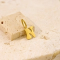 Detailed close-up of polished gold letter N pendant on minimalist textured stone background - Letter-N / Steel