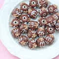 Detailed top view of chocolate-style cylinder loose beads on a vintage white plate - Chocolate Bead Coffee Cream Flower