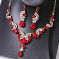 Close-up of gold-tone bridal jewelry set with red teardrop crystals and white rhinestones - Necklace and Earring Set / Gold/Red/White