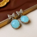 Detalle macro de pendientes de resina azul vintage con lazo plateado y espiral - Colgante de Lazo Redondo Azul / Azul