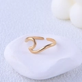 Minimalist gold wavy open ring made of titanium steel on a white decorative stone base - Gold