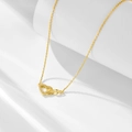 Elegant gold infinity heart necklace with small zircons displayed on white geometric stand - 925 Silver / Gold