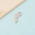 Macro shot of silver baby feet charm pendant with a polished mirror finish for DIY jewelry - Silver Tone Double Hole Foot