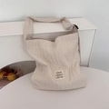 Detail van een crèmekleurige canvas shopper met plooien en een minimalistisch label - Beige