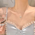 Close-up of a silver titanium steel bow necklace worn by a model in light blue dress - Silver Cat's Eye Bowknot