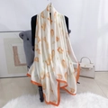 Detailed drape of white and orange tulip pattern silk scarf on a soft chair - Yellow