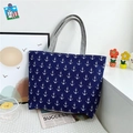 Blue canvas tote bag featuring white anchor patterns and grey handles on a white surface - Anchor Navy Blue