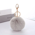Detail of light grey faux rabbit fur pompom keychain with golden metal hardware - Gray
