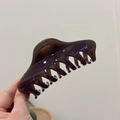 Detailed view of a 12cm transparent dark brown shark hair claw clip held in hand - Dark Gray