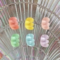 Close-up of colorful translucent resin bean accessories on an iridescent shell surface - Letter E