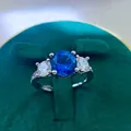 Macro detail of a silver three-stone ring with a blue gemstone in a green velvet box - A2 Open Type / Blue