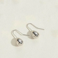 Detailed view of silver teardrop hoop earrings on a textured off-white background - Single Bead / Platinum Color